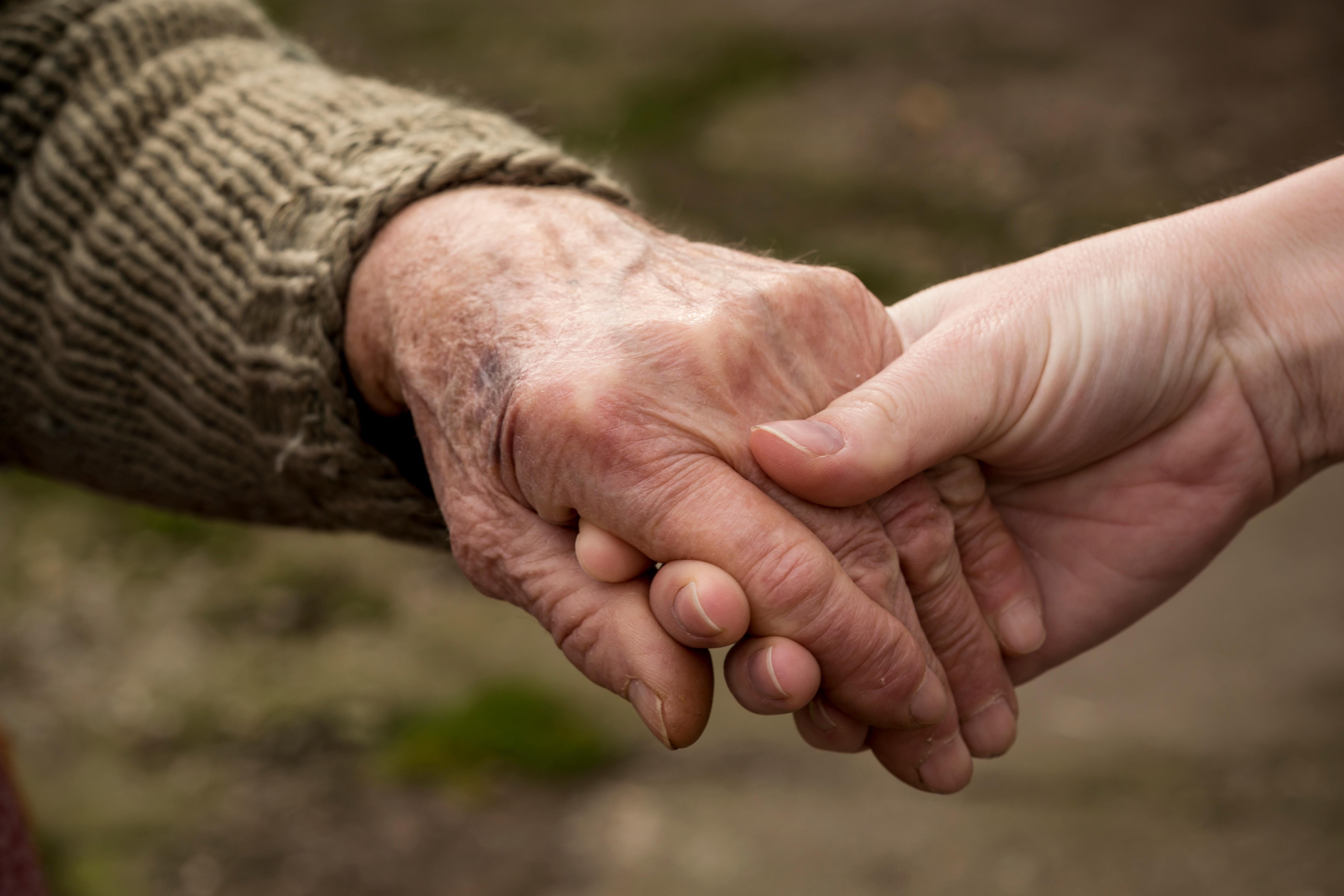 a picture of a hand holding and another person's hand (a younger hand holding an elderly hand)